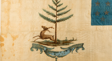 美国雄鹿旗上有鹿，有鹿, pine tree, 印有“美国雄鹿”字样的大圆钻, 在图像的顶部有一个较小的带有首字母“J-G-W-H”的圆饰."